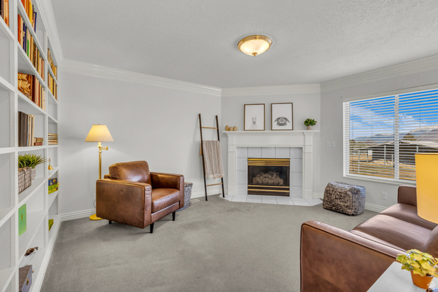 1060 West 2620th Street South Mapleton, UT 84664 - Photo 34 of 87 Living room with a tile fireplace, ornamental molding, light carpet, and a textured ceiling