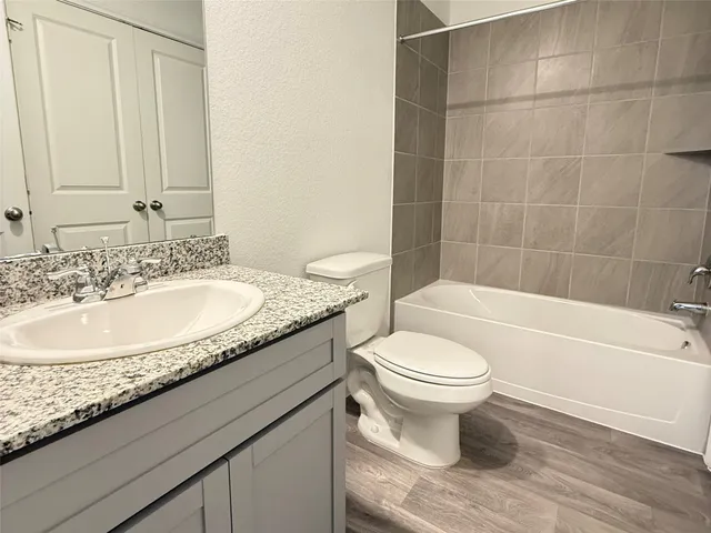 a bathroom with a granite countertop toilet a sink and bathtub