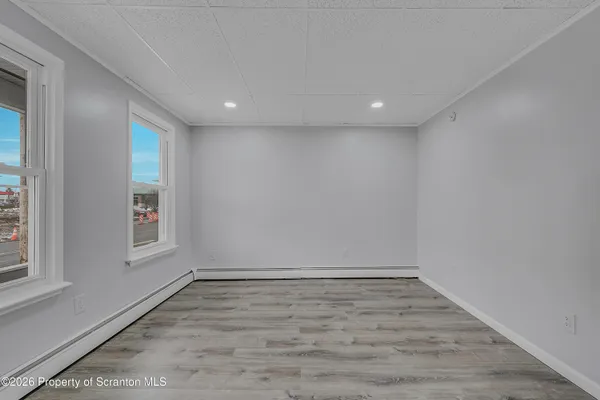 an empty room with wooden floor and windows