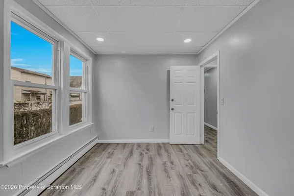 a view of empty room with wooden floor and fan
