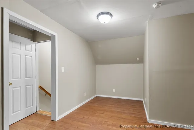an empty room with wooden floor chandelier fan and windows