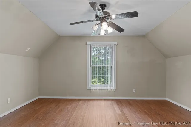 an empty room with wooden floor closet and fan