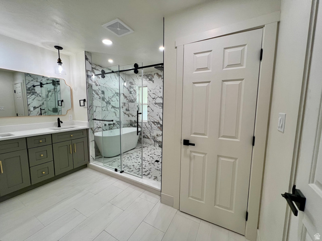 812 East Bates Cyn Road Tooele, UT 84074 - Photo 43 of 144 Spacious bathroom featuring a freestanding tub within a glass-enclosed shower, dual vanity with green cabinetry, white countertops, and light tile flooring