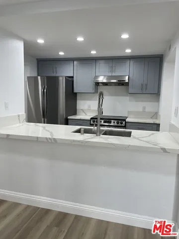 a view of kitchen with stainless steel appliances kitchen island sink refrigerator and cabinets