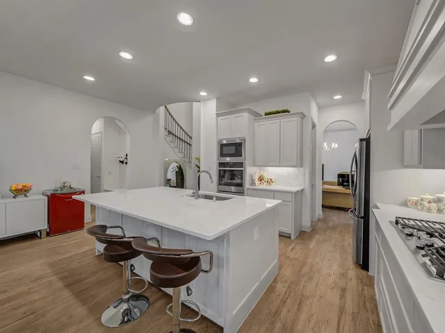 a large white kitchen with wooden floor and a sink