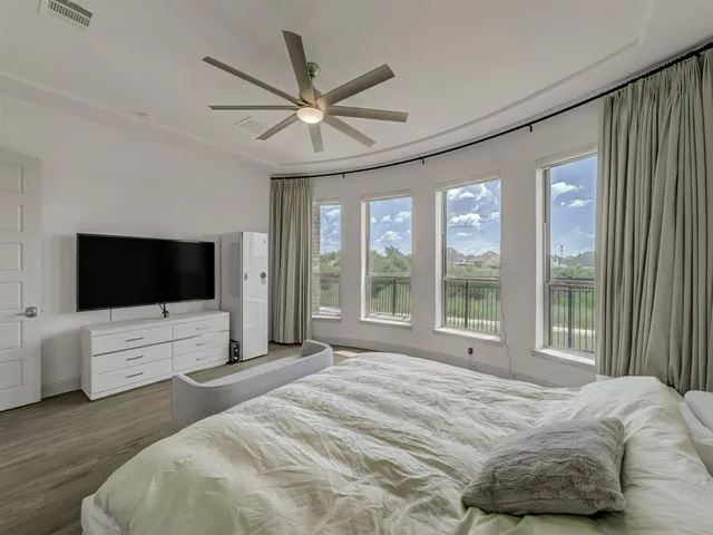 a bedroom with a bed chandelier and a large window