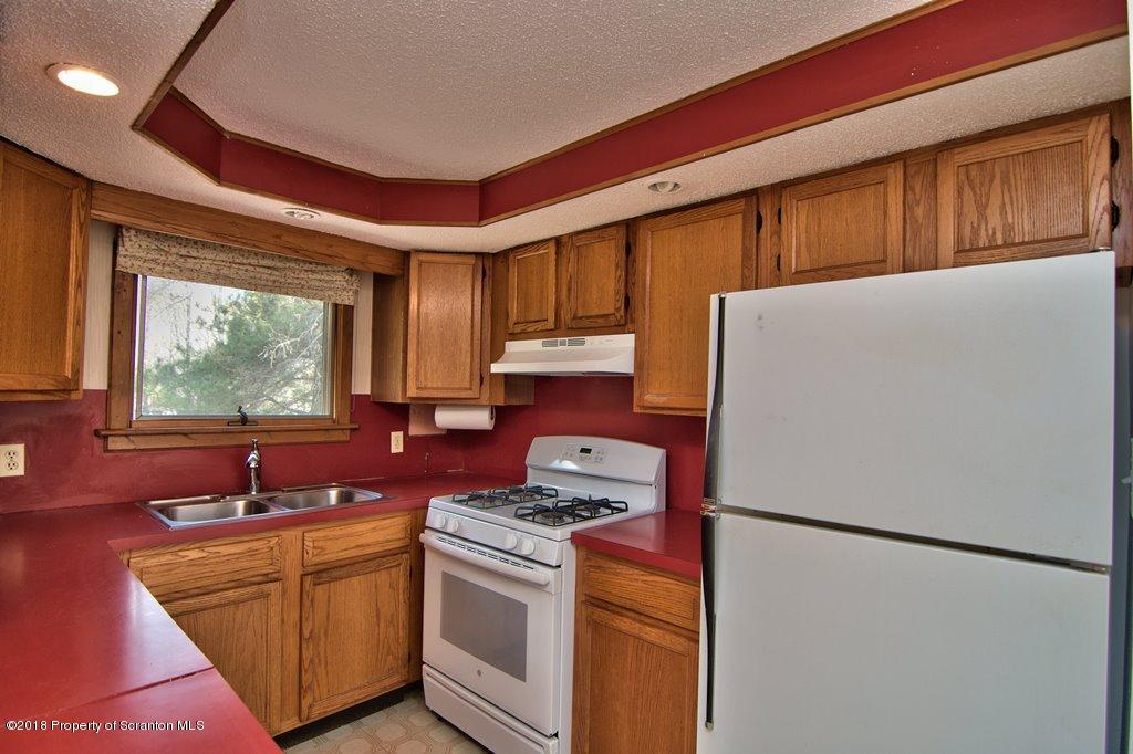 3585 Hornbaker Cemetary Road Moscow, PA 18444 - Photo 5 of 46 a kitchen with stainless steel appliances granite countertop a refrigerator a sink a stove a dining table and chairs with wooden floor