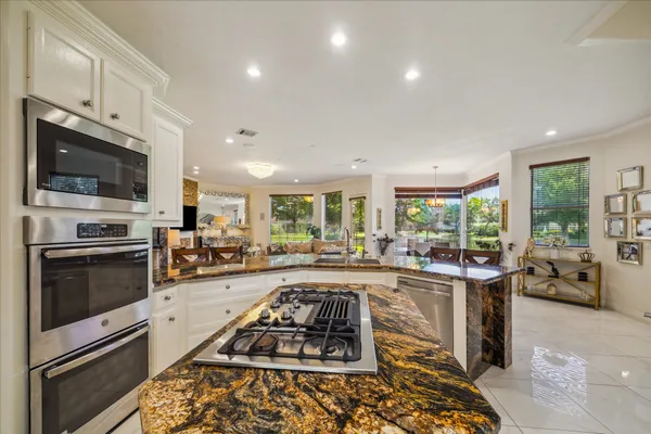 a large white kitchen with granite countertop a stove and a sink