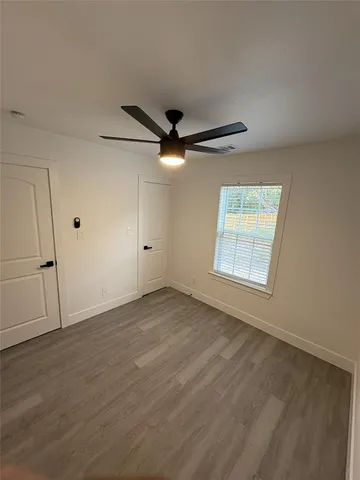 an empty room with ceiling fan and windows