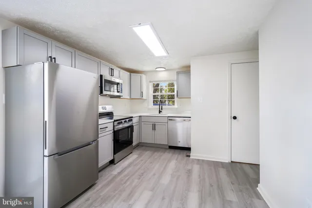 a kitchen with a refrigerator a sink and dishwasher with wooden floors