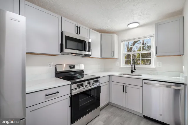 a kitchen with cabinets stainless steel appliances a sink and a window