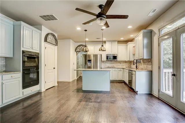 a large kitchen with cabinets wooden floor and stainless steel appliances
