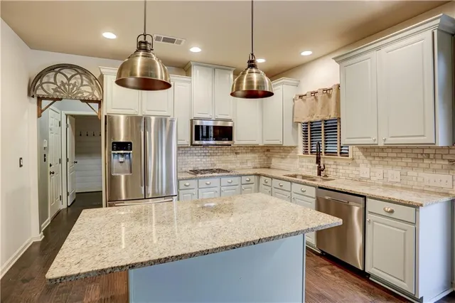 a kitchen with stainless steel appliances granite countertop a sink a refrigerator and a wooden cabinets