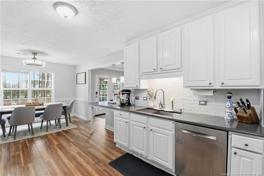 212 Lennox Loop Raeford, NC 28376 - Photo 14 of 47 a kitchen with white cabinets sink dining table and chairs