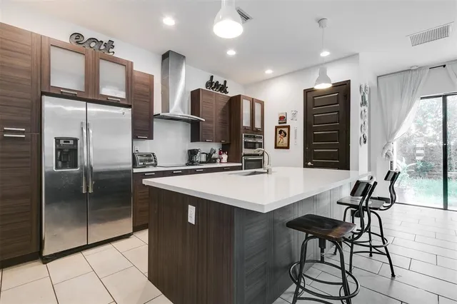 a kitchen with stainless steel appliances kitchen island granite countertop a refrigerator a stove and a sink with wooden floor