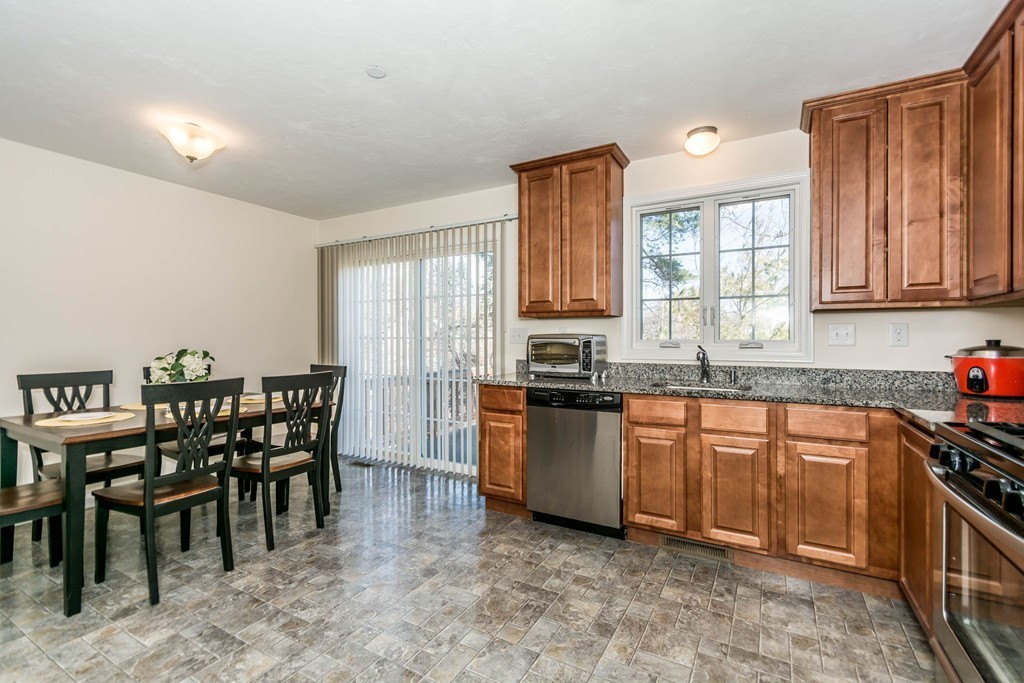 41 Boston Road, Unit 124 Billerica, MA 01862 - Photo 6 of 18 a kitchen with stainless steel appliances granite countertop a stove top oven a sink a dining table and chairs with wooden floor