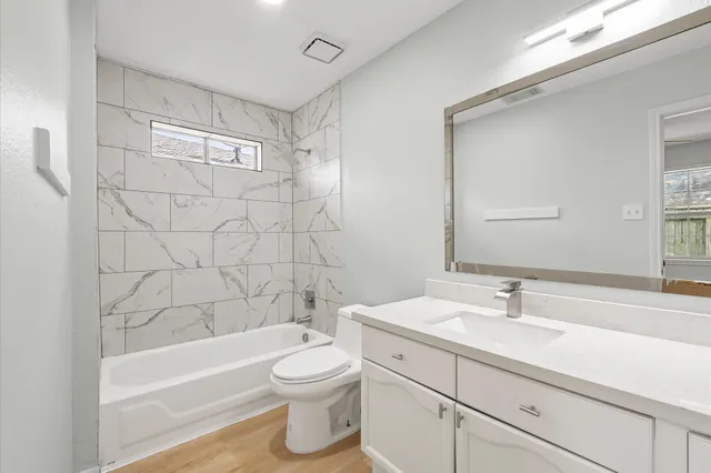 an empty room with wooden floor chandelier fan and windows