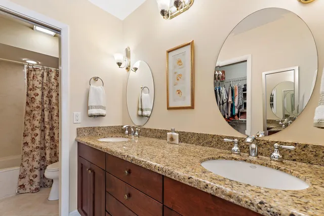 a bathroom with a granite countertop double vanity sink and a mirror