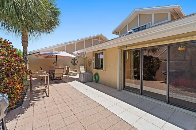 a view of patio with chairs and table under an umbrella