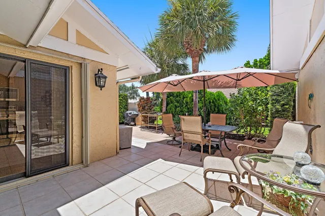 a view of a patio with table and chairs potted plants and a palm tree