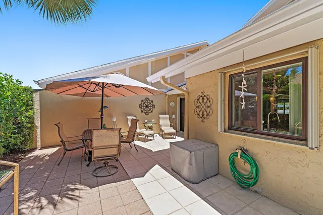 a view of patio with chairs and table under an umbrella with a barbeque