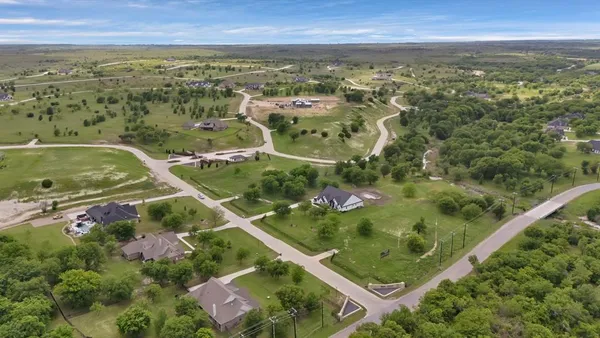 an aerial view of residential houses with outdoor space and trees