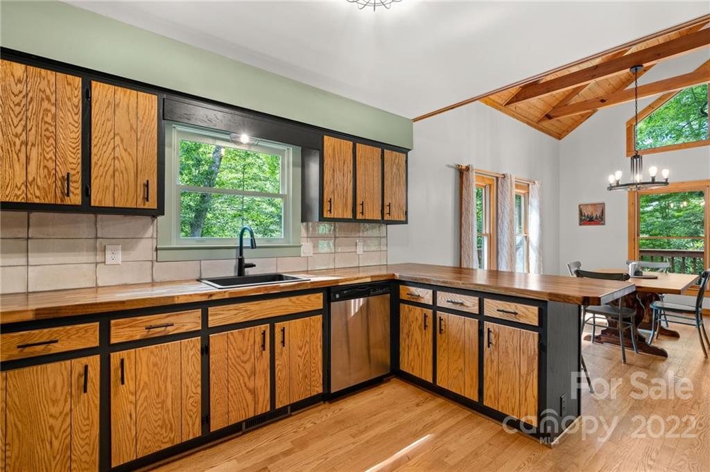 7 Twin Mountain View Road Canton, NC 28716 - Photo 19 of 36 a kitchen with wooden cabinets a sink dishwasher a stove and a large window with wooden floor