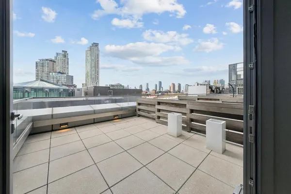 a roof deck with table and chairs and potted plants