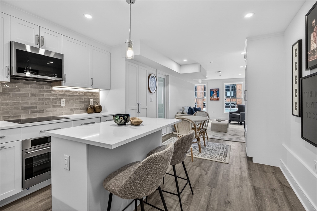 149 Charles Street, Unit 4 Boston, MA 02114 - Photo 1 of 11 a kitchen with stainless steel appliances a table chairs refrigerator and microwave
