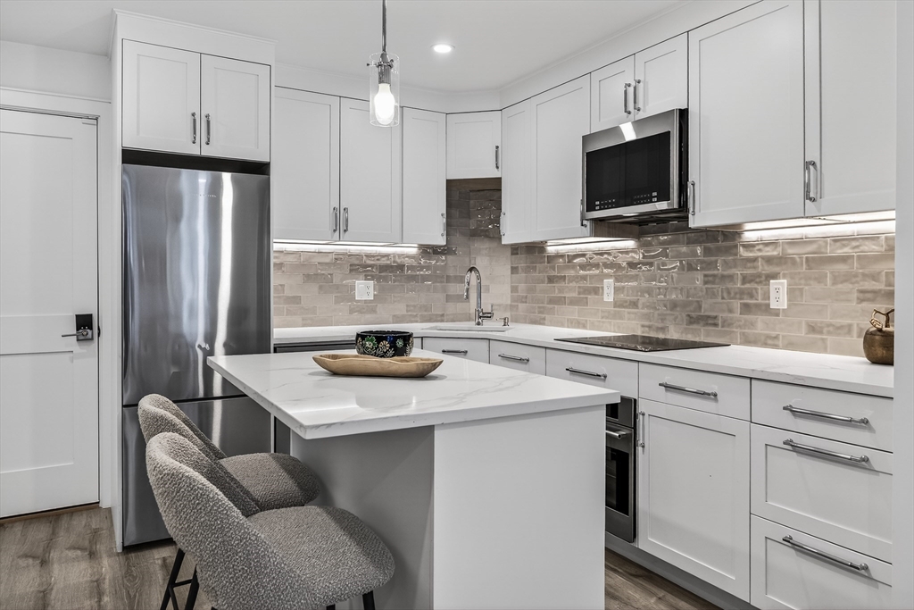149 Charles Street, Unit 4 Boston, MA 02114 - Photo 2 of 11 a kitchen with stainless steel appliances granite countertop a sink refrigerator stove microwave and cabinets