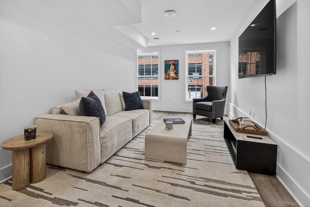 149 Charles Street, Unit 4 Boston, MA 02114 - Photo 3 of 11 a living room with furniture a flat screen tv and kitchen view