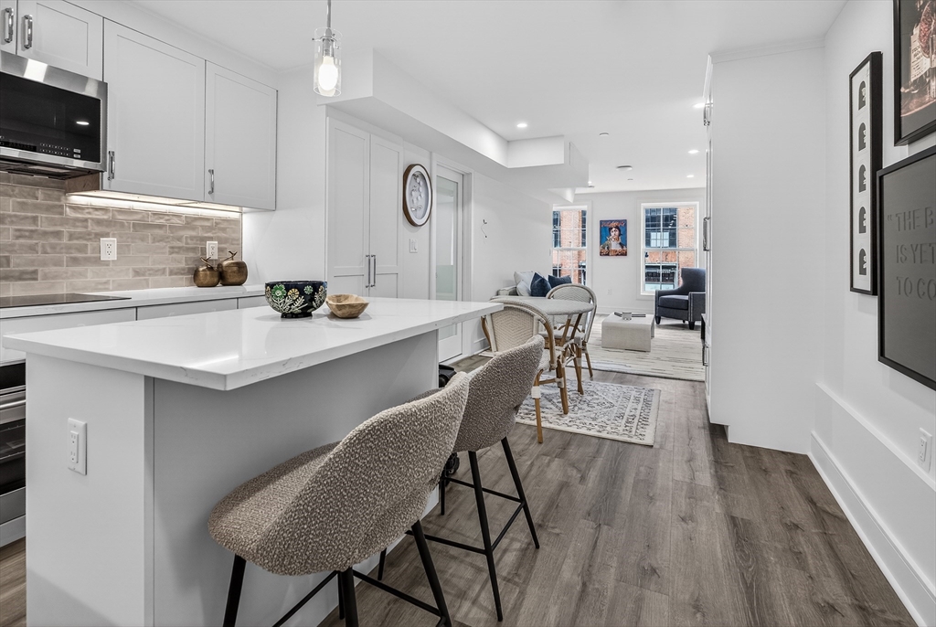 149 Charles Street, Unit 4 Boston, MA 02114 - Photo 7 of 11 a kitchen with a table chairs microwave and cabinets