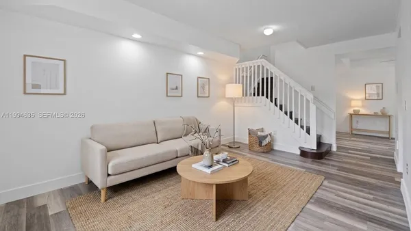 a living room with couches and a dining table with wooden floor
