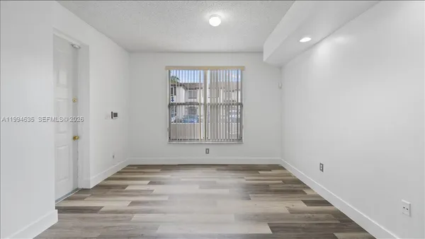 a view of an empty room with wooden floor and a window