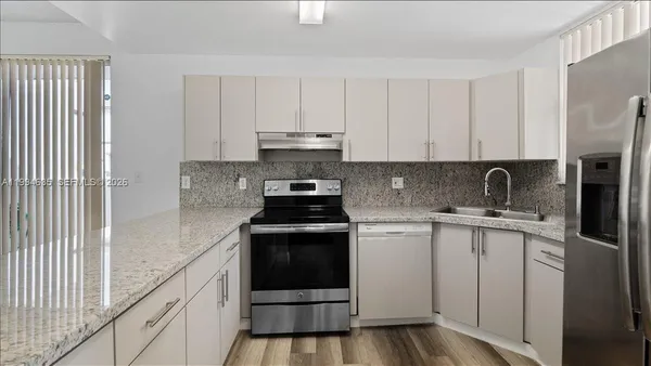 a kitchen with stainless steel appliances granite countertop a stove a sink and a refrigerator