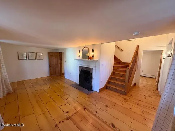 a view of a livingroom with wooden floor and staircase