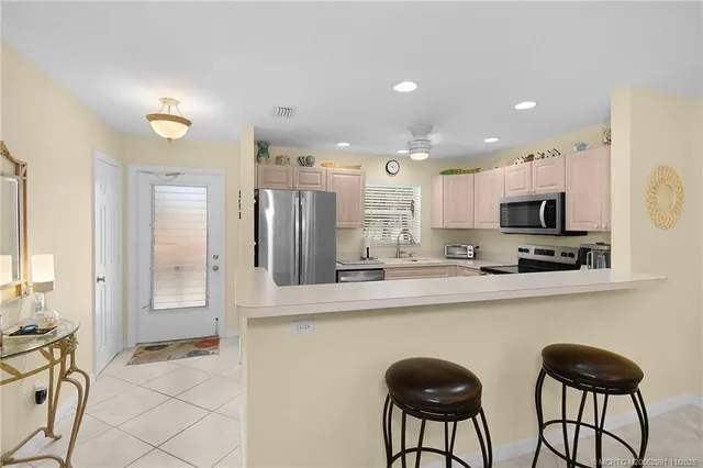 a kitchen with stainless steel appliances granite countertop a stove a sink a refrigerator white cabinets and chairs