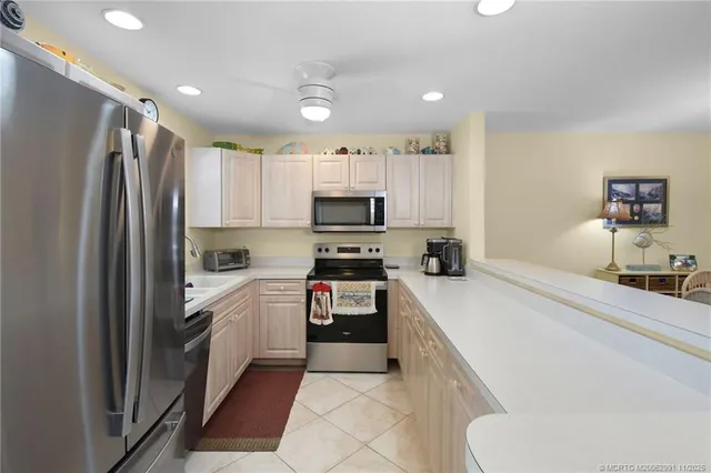 a kitchen with granite countertop a refrigerator sink and white cabinets