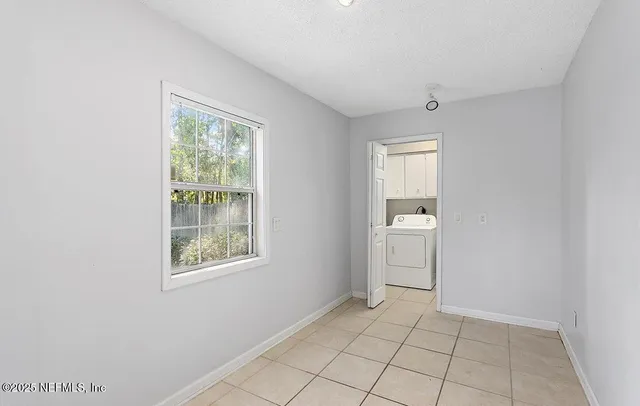 a view of an empty room with a window and cabinet