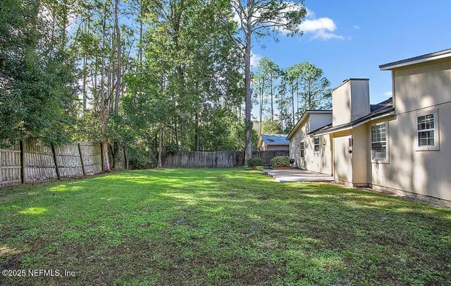 a view of a house with a big yard and large trees