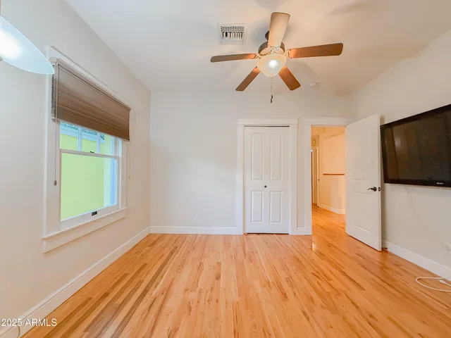 a view of empty room with wooden floor and fan