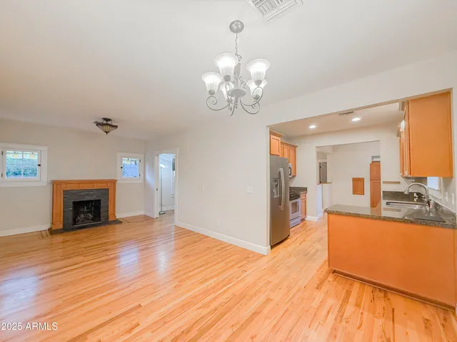 a view of a livingroom with a fireplace wooden floor and a kitchen space