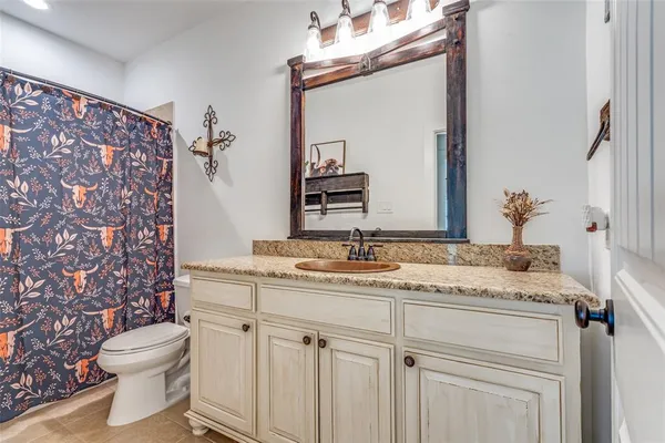 a bathroom with a granite countertop sink vanity mirror and toilet