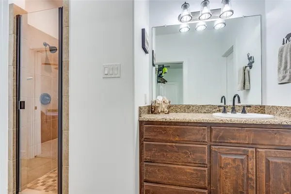 a bathroom with a granite countertop sink a mirror and a shower