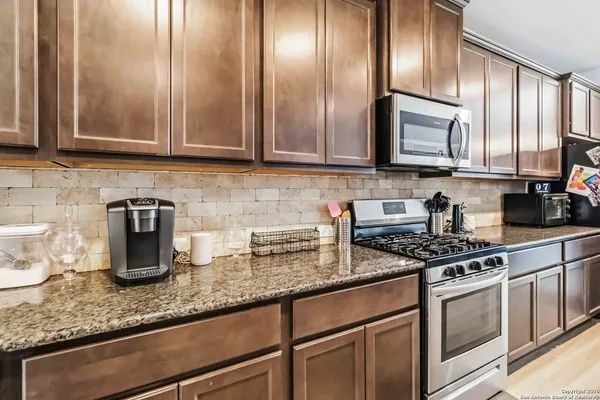 a kitchen with granite countertop stainless steel appliances a sink a stove and cabinets