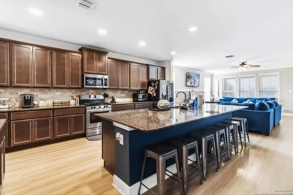 a kitchen with stainless steel appliances granite countertop a stove a sink dishwasher a microwave oven and a dining table with wooden floor