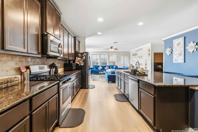 a large kitchen with stainless steel appliances granite countertop a stove refrigerator and a sink