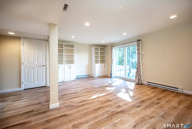 a view of an empty room with wooden floor and entryway