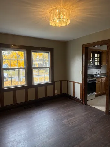 a view of an empty room with kitchen and window