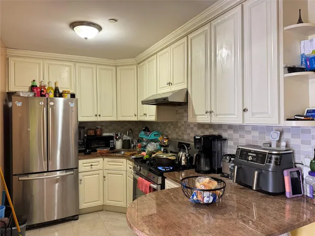 a kitchen with stainless steel appliances granite countertop a refrigerator sink stove and white cabinets